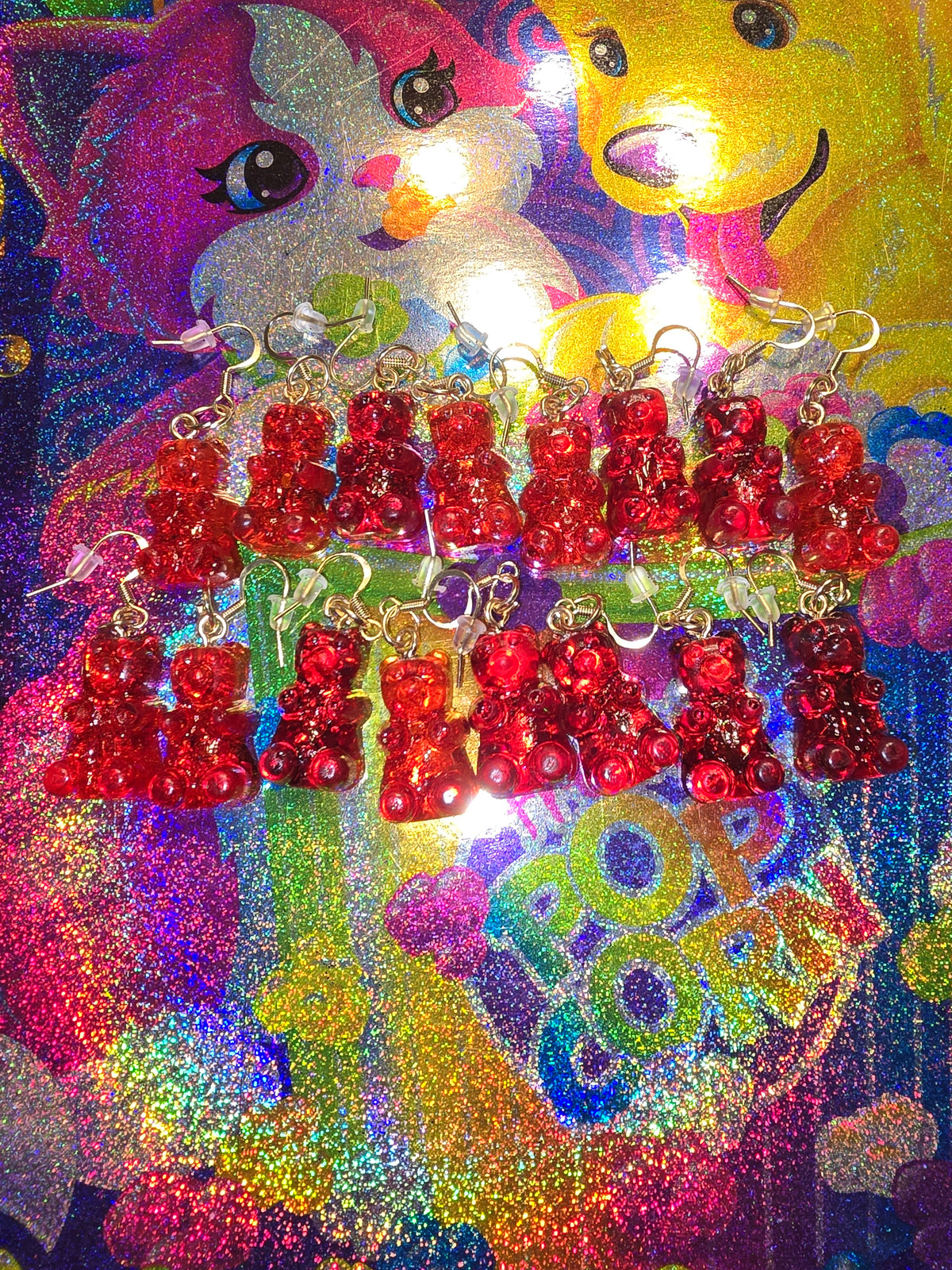 Gold tone earrings with red gummy bears on a multicolored background